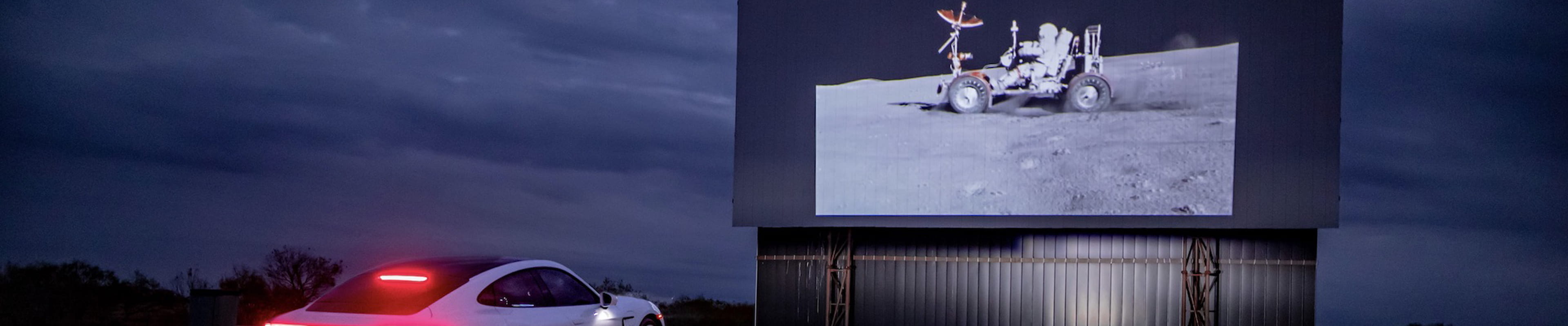 Porsche in front of moon landing billboard