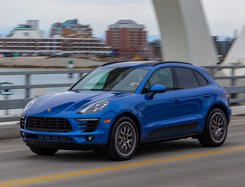 Blue Porsche Macan parked in front of photo gallery building.