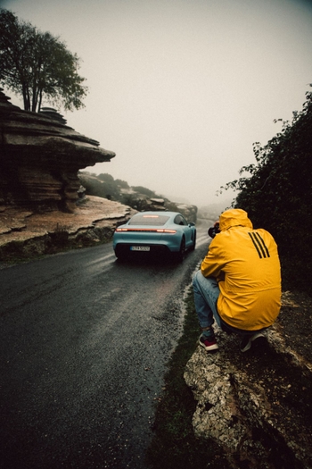 man taking picture of taycan on road
