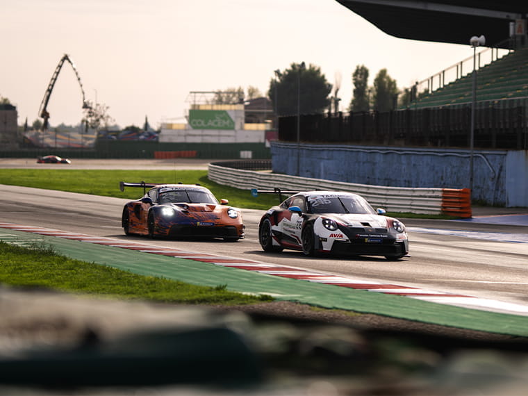 Zwei Porsche Sportwagen fahren hintereinander auf einer Rennstrecke.