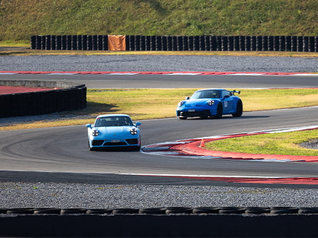 Zwei Porsche Sportwagen fahren auf einer Rennstrecke.