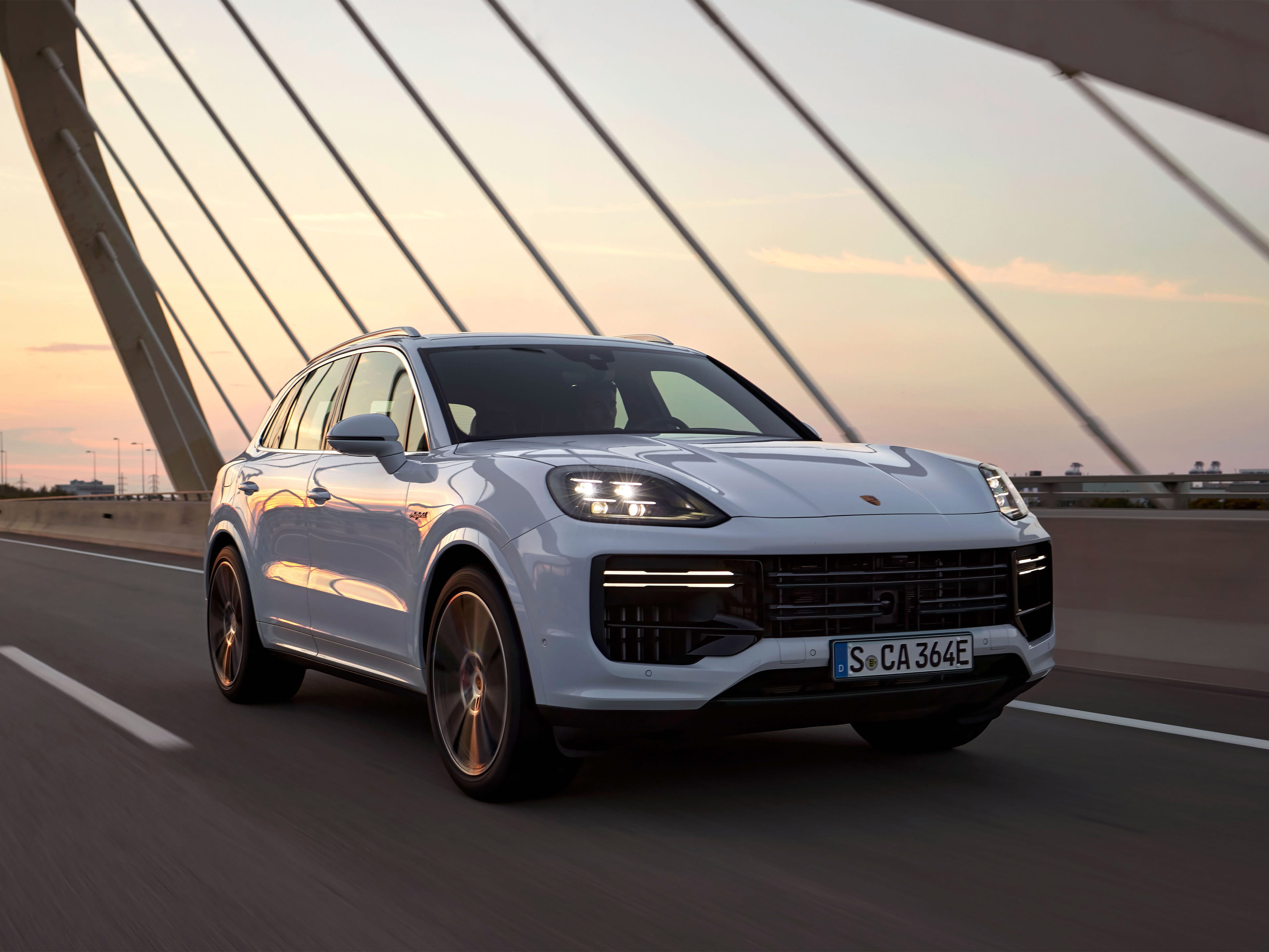 Ein Porsche Sportwagen fährt in der Abenddämmerung über eine Brücke.