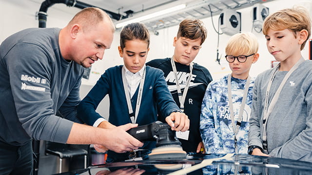 Kinder bekommen die Autowerkstatt gezeigt.